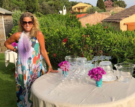 Nina Snow standing next to a table full of wine glasses in the sunny yard of an Italian villa.